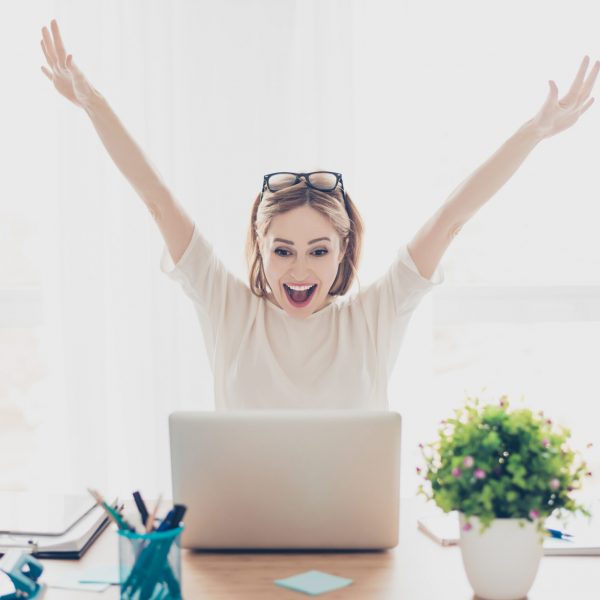 Happy excited successful businesswoman triumphing with laptop