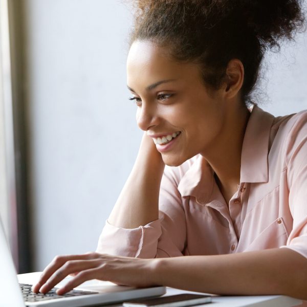 Close up portrait of a beautiful young woman smiling and looking at laptop screen